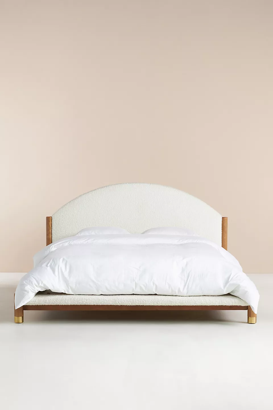 A bed with a wooden frame and a white upholstered headboard.