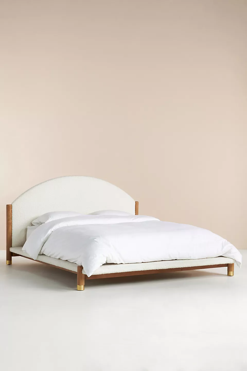 A bed with a wooden frame and a white upholstered headboard.