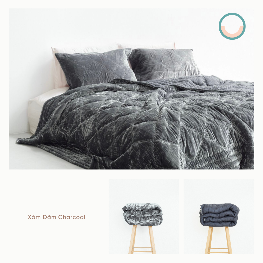 A bed with a grey silk velvet comforter and pillows.