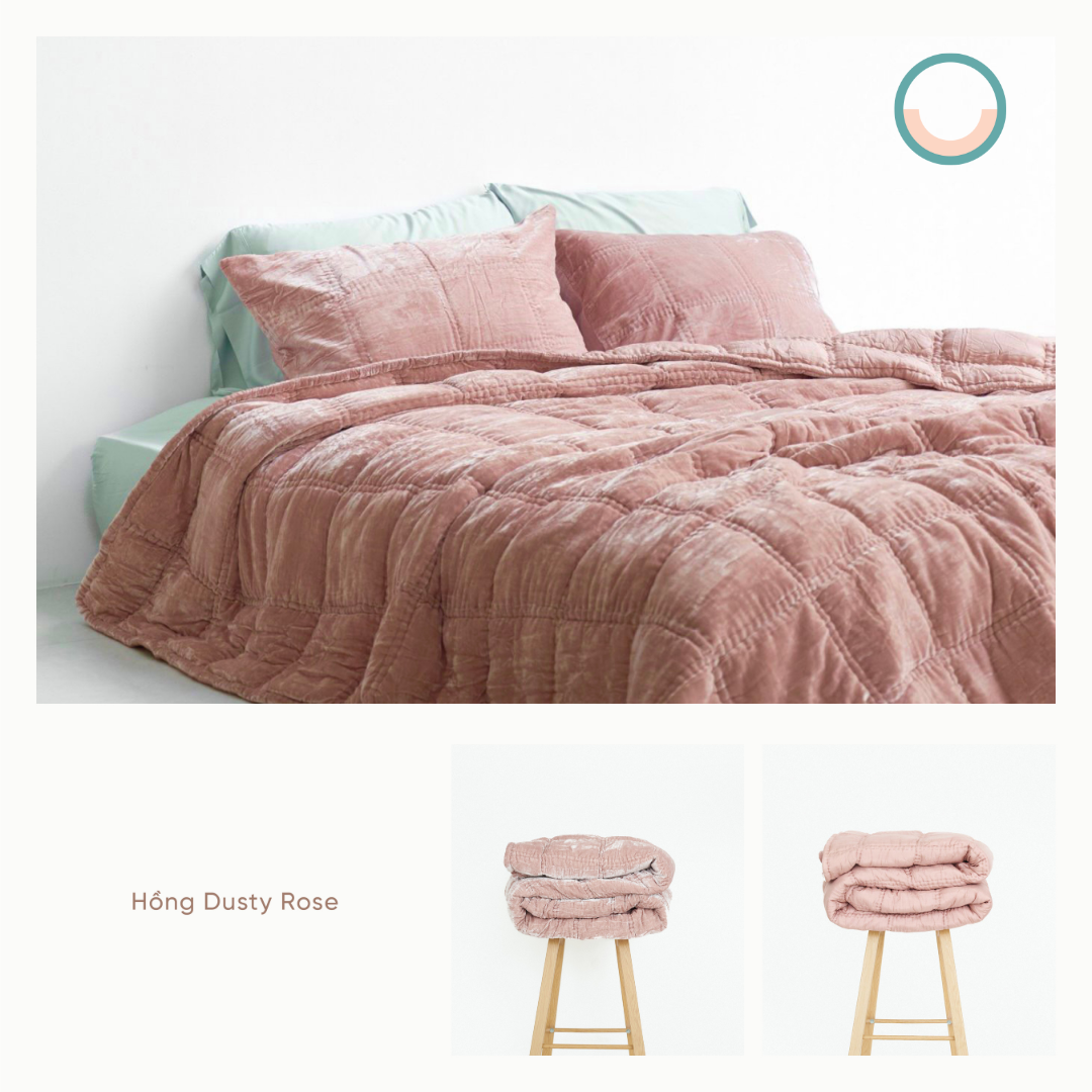 A bed with a pink silk velvet comforter and pillows.